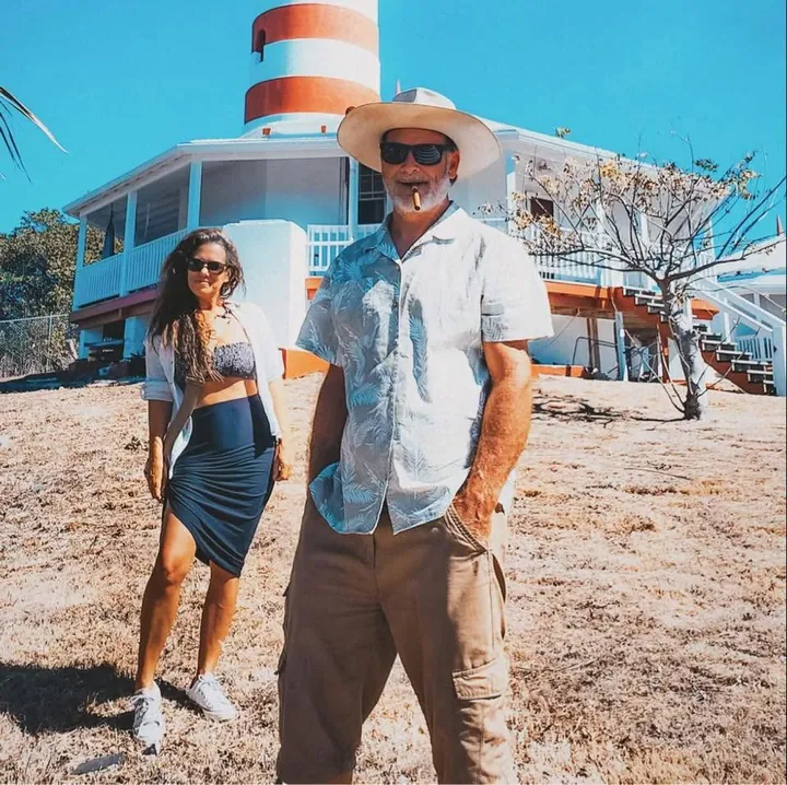 Mel and David in front of a red and white striped lighthouse, David with a cigar