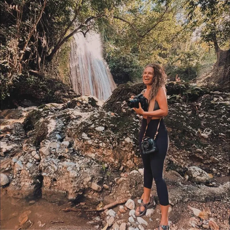 Mel laughing at a waterfall with her cameras